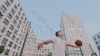 野心勃勃的强壮的家伙做特技和技巧与<strong>篮球</strong>在城市景观背景。 <strong>运球</strong>，旋转，旋转